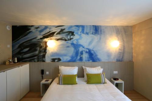 a bedroom with a bed with a painting on the wall at SOWELL HOTELS Domaine de la Petite Isle in LʼIsle-sur-la-Sorgue