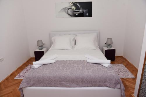 a bedroom with a large white bed with two lamps at Lux Apartman Casablanca in Pluzine