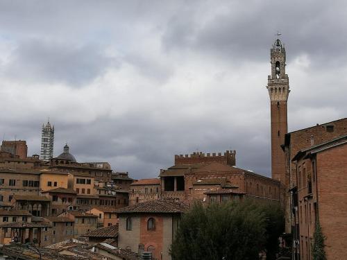 a tall tower with a clock on top of a city at Panorama di Siena in Siena