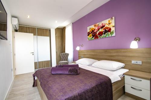Habitación de hotel con cama con pared morada en Villa Evoque - Adriatic Luxury Villas, en Zadar