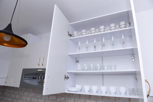 a kitchen with white shelves with glasses on them at Lux Apartman Casablanca in Pluzine