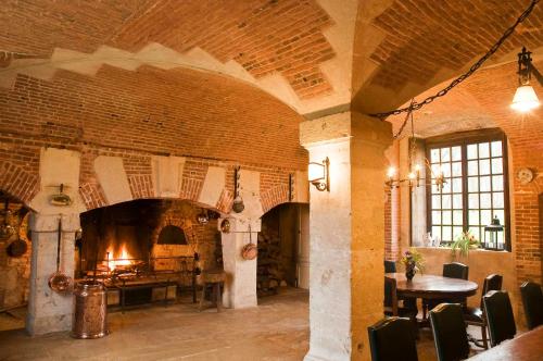 a large brick room with a fireplace and a table at Le château de Bonnemare - Bed and breakfast in Radepont