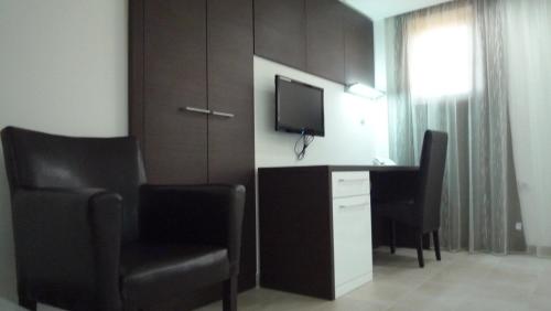 a room with a desk with a television and chairs at Apartments Good Night in Niš