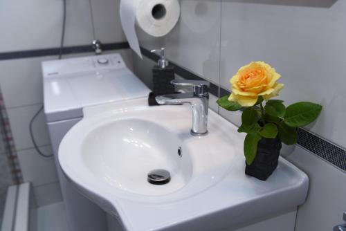 a bathroom sink with a vase with a yellow rose in it at Lux Apartman Casablanca in Pluzine