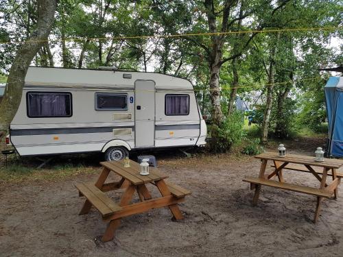 a white caravan parked next to two picnic tables at Przyczepy Kemping Polaris Półwysep Helski in Chałupy
