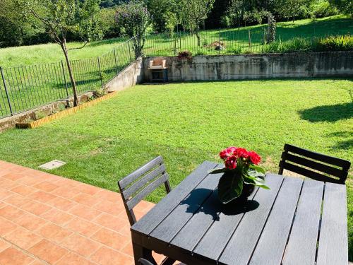 a wooden picnic table with a vase of flowers on it at Strawberry House in Colico