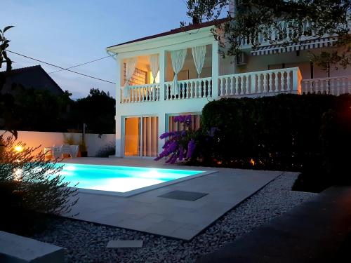 a swimming pool in front of a house at night at Holiday Home Villa Emma in Debeljak