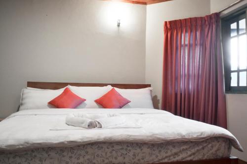 a bedroom with a bed with red pillows at Samri Holiday Bunglow in Nuwara Eliya