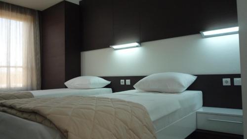 a bedroom with two beds and two lights on the wall at Apartments Good Night in Niš