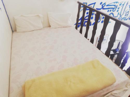 a bed with a yellow blanket and two pillows at badawiya farafra hotel in Qasr Al Farafirah