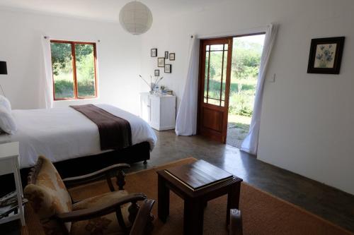 a bedroom with a bed and a table and a chair at Seven Fountains Farm in Grahamstown