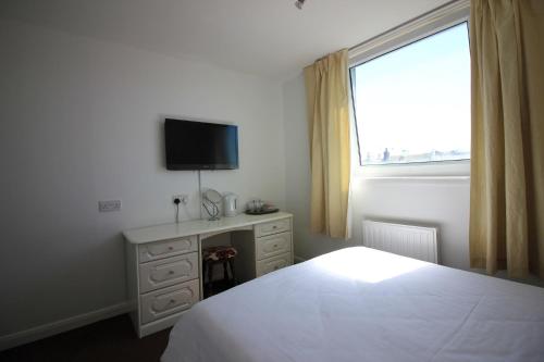 a bedroom with a television and a bed at Seafield House in Brighton & Hove