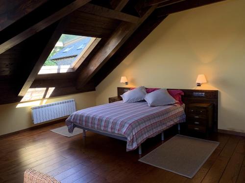 a attic bedroom with a bed and a window at Ca Don Rafel in Castanesa
