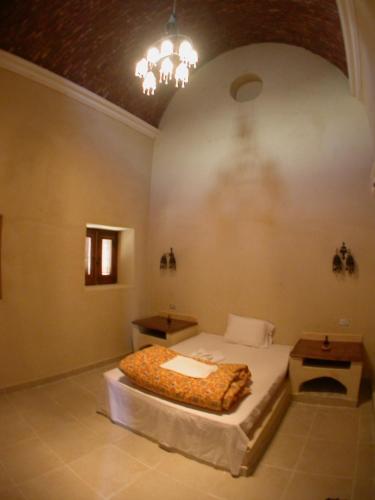 a bedroom with a bed and a chandelier at badawiya farafra hotel in Qasr Al Farafirah