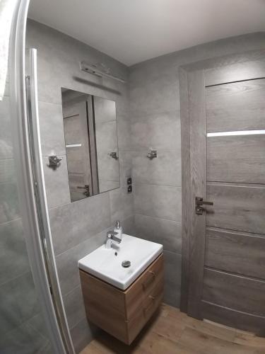 a bathroom with a sink and a shower with a mirror at Pokoje Sandra I in Łeba
