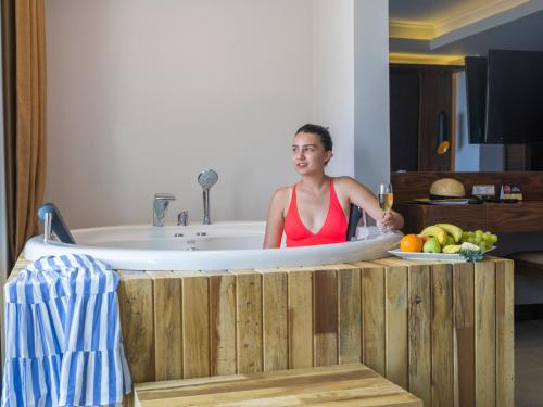 una mujer sentada en una bañera con una copa de vino en Orka Sunlife Resort Hotel and Aquapark, en Ölüdeniz