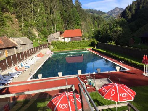 a pool with umbrellas and chairs and a house at Appartement Veronika in Öblarn