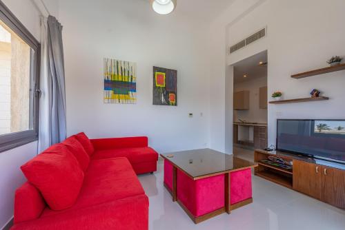 sala de estar con sofá rojo y TV en Golden Apartments Pool View 1-Bedroom Apartment in G-Cribs, El Gouna, en Hurghada