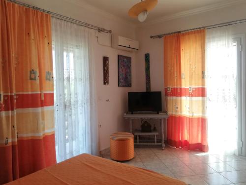 LangadhákiaにあるPaliorouga Lodge Zakynthosのカーテン、テレビ、ベッドが備わるベッドルーム1室が備わります。