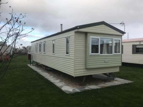 a yellow tiny house sitting in a yard at 8 Berth on The Grange (Summer) in Ingoldmells