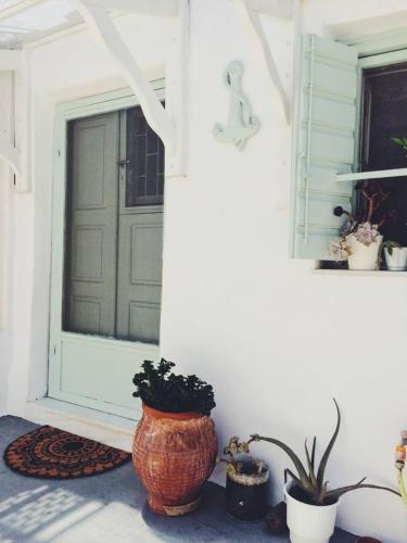 a porch with a door and some potted plants at The Oceanographer's Home, A Chora Hideaway in Serifos Chora