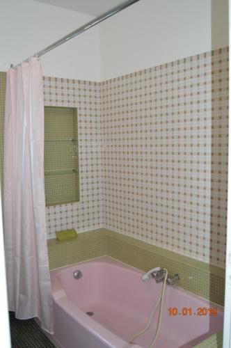 La salle de bains est pourvue d'une baignoire rose et d'un miroir. dans l'établissement Maison de vacances, à Saint-Sulpice-de-Royan