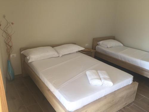two beds in a room with white sheets and towels at Xuxi Apartments in Lukovë