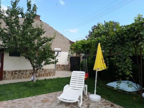 a patio with a chair and a yellow umbrella at Къща за гости с минерална вода "Терма Асклепий" in Kyustendil