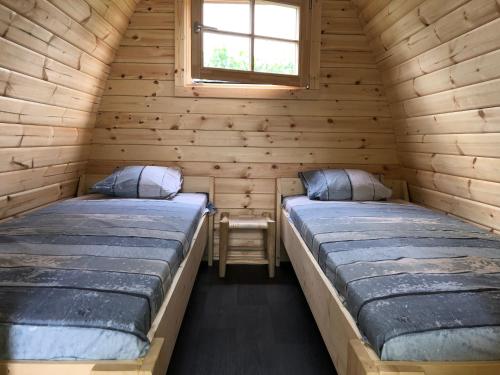 two beds in a log cabin with a window at Trekkershut/kampeerhut in Hulst