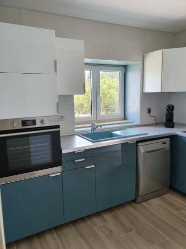 a kitchen with blue and white cabinets and a sink at PÉROLA D'ÓBIDOS t2 in Óbidos