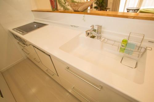 ein weißes Waschbecken in einer Küche mit einer Theke in der Unterkunft Kunigami-gun - House / Vacation STAY 42280 in Onna