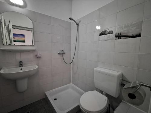 a white bathroom with a toilet and a sink at Vila Tropicana in Eforie Sud