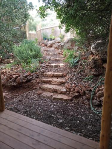 a stone path in a garden with a wooden walkway at THE HOUSE IN THE OAKS הבית באלונים in Amirim
