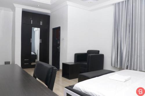 a room with a bed and two chairs and a table at House X in Abuja