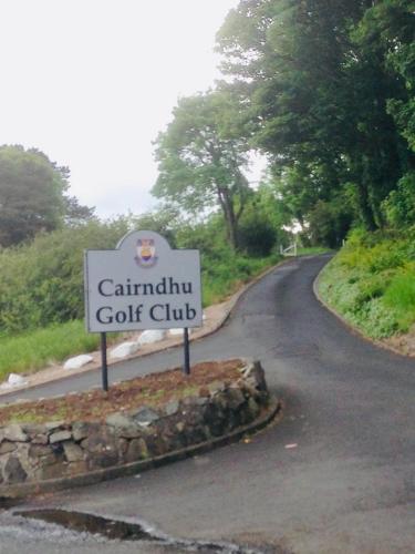 a sign for a golf club on a road at Ballygally Seaview Cottage in Larne