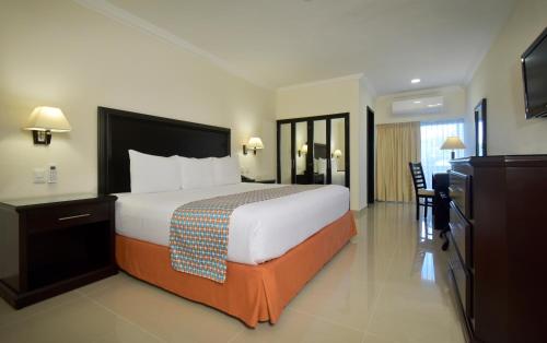 a hotel room with a large bed and a television at Hotel Bonampak in Cancún