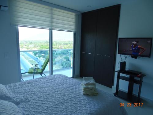 a bedroom with a bed and a tv and a window at Tayrona Beach Bello Horizonte in Santa Marta