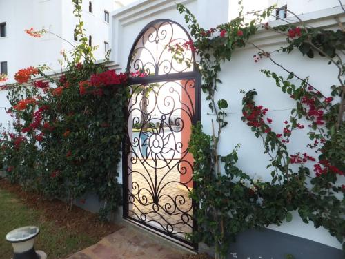 a gate to a house with flowers at Appartement haut standing calme + piscines + WIFI in Asilah
