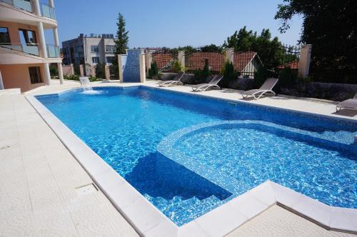 a large swimming pool with chairs and a building at Vello Apartments in Byala