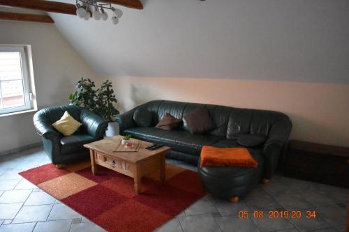 a living room with a black leather couch and a coffee table at Ferienhaus Harzvorland in Ballenstedt
