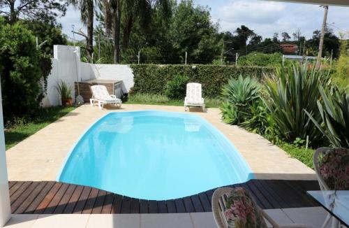 a swimming pool in a yard with two chairs at CASA DE CAMPO NA CIDADE DA SAÚDE in Serra Negra