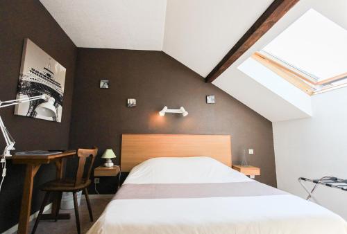 Schlafzimmer mit einem Bett, einem Schreibtisch und einem Fenster in der Unterkunft Hotel Restaurant De La Poste Mulhouse Ottmarsheim in Bantzenheim