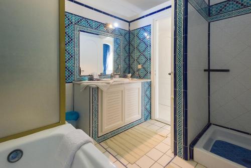 a bathroom with a tub and a sink and a mirror at Villa Phoenicia in Hammamet