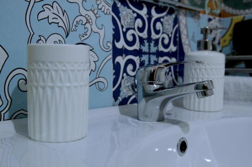 2 tasses assises sur un lavabo avec un robinet dans l'établissement Giulia's house apartments, à SantʼAntonio Abate