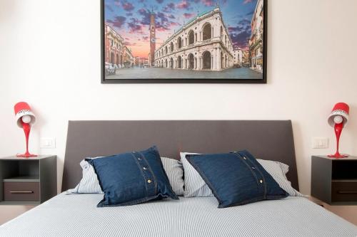 ein Bett mit blauen Kissen und ein Gemälde an der Wand in der Unterkunft Charmant Palladio - Vicenza City Center in Vicenza