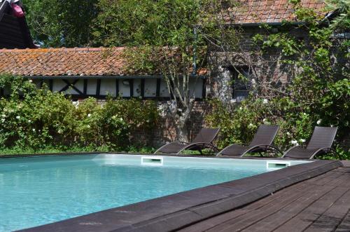 une piscine avec deux chaises à côté d'une maison dans l'établissement B&B La tour blanche, à Forest-Montiers