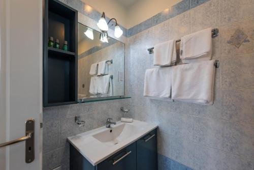 a bathroom with a sink and a mirror and towels at Theoxenia Hotel Apartments in Chrani