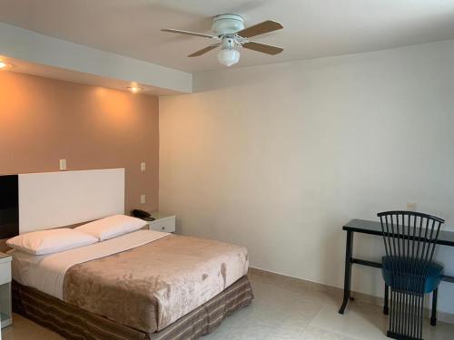 a bedroom with a bed and a table and a ceiling fan at Hotel Cali Blvd. in Guadalupe