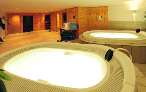 a bathroom with two large tubs in a room at Country Wellnesshotel Bündnerhof in Samnaun