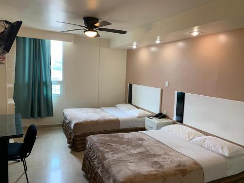 a hotel room with two beds and a ceiling fan at Hotel Cali Blvd. in Guadalupe